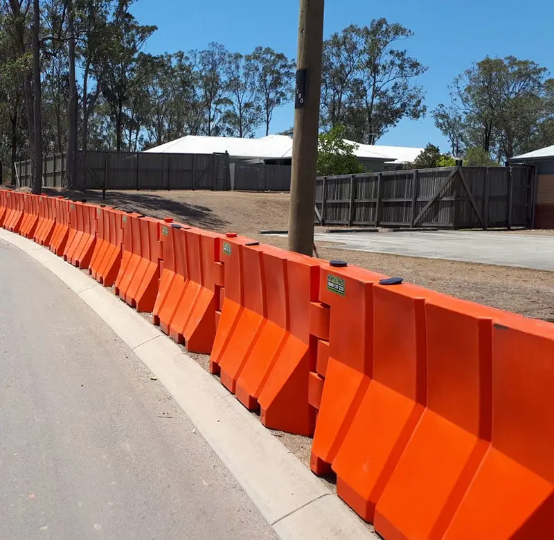 Orange water barriers installed along a roadside work area